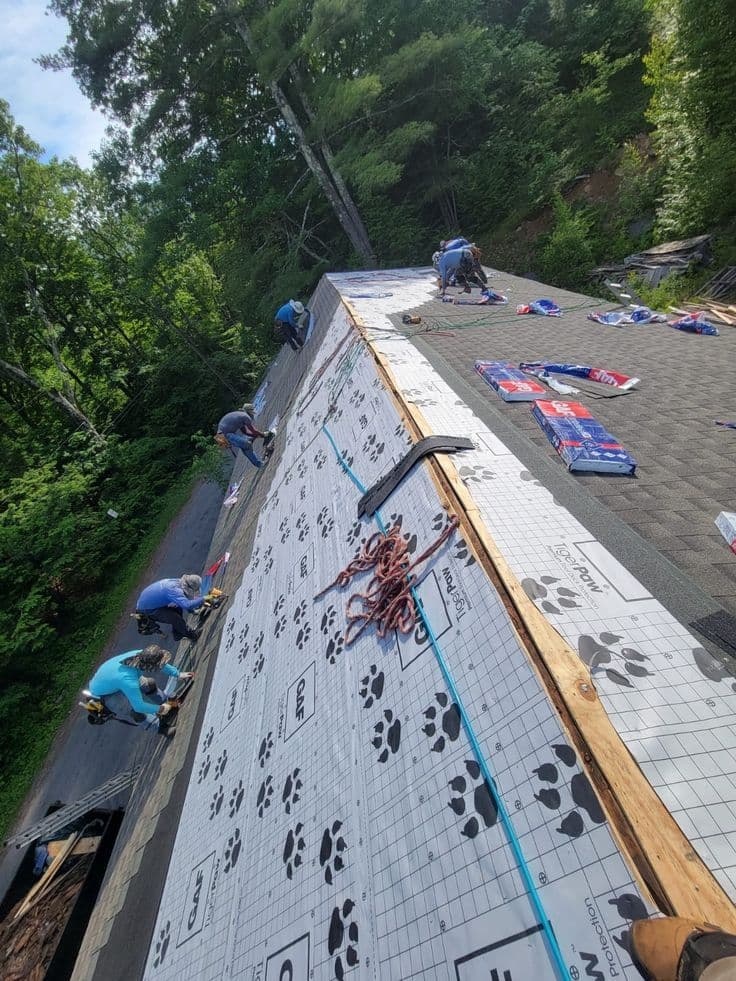 Crew laying underlayment and shingles on a residential roof