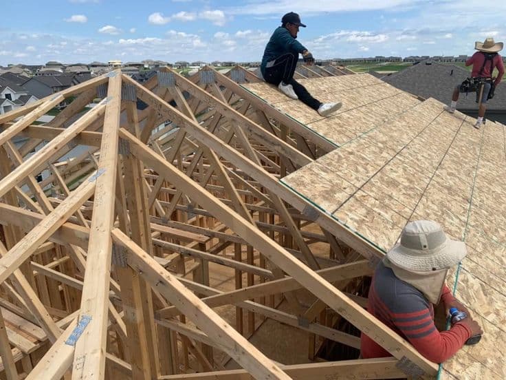 Roofers laying sheathing panels across new roof trusses in Doylestown